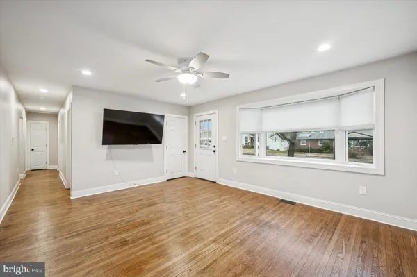 a view of an empty room with window and wooden floor