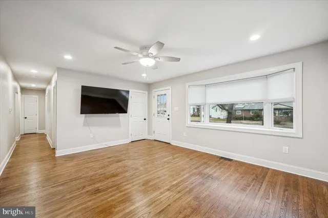 a view of an empty room with window and wooden floor