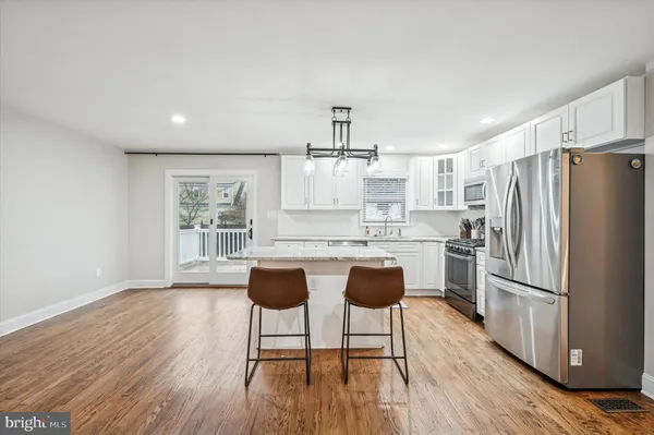 a kitchen with stainless steel appliances granite countertop a refrigerator a sink dishwasher a dining table and chairs with wooden floor