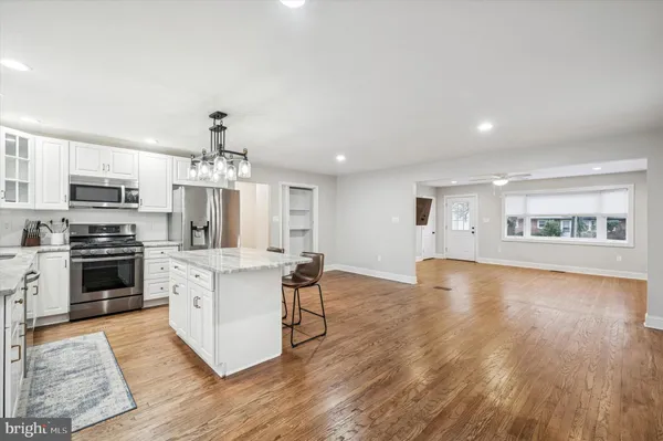 a kitchen with stainless steel appliances a stove top oven a sink dishwasher a refrigerator and a dining table with wooden floor