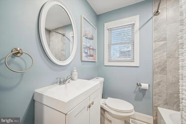 a bathroom with a toilet a sink a mirror and a window