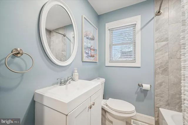 a bathroom with a toilet a sink a mirror and a window