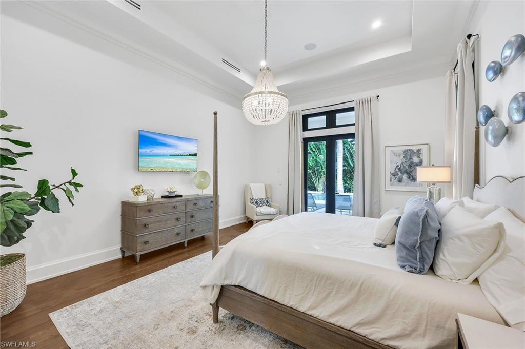 3200 Crayton Road Naples, FL 34103 - Photo 14 of 30 a bedroom with a bed and a chandelier