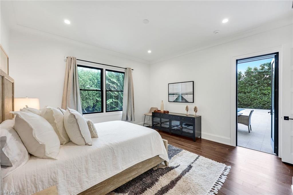 3200 Crayton Road Naples, FL 34103 - Photo 21 of 30 a bedroom with a large bed and wooden floor