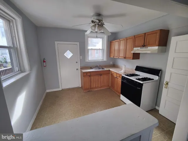 a kitchen with stainless steel appliances granite countertop a sink a stove a refrigerator cabinets and a window