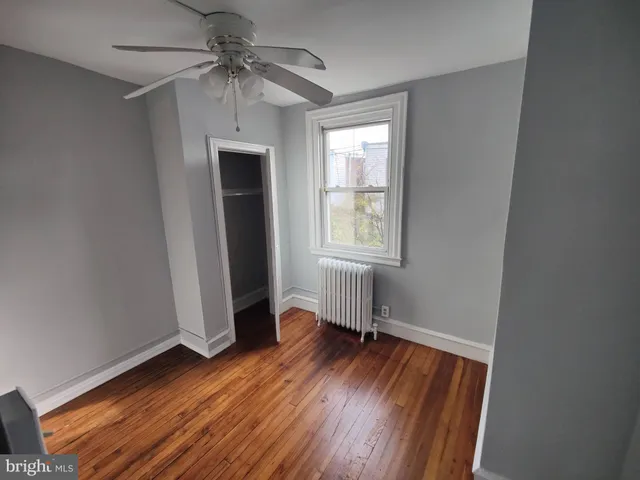 an empty room with wooden floor fan and windows