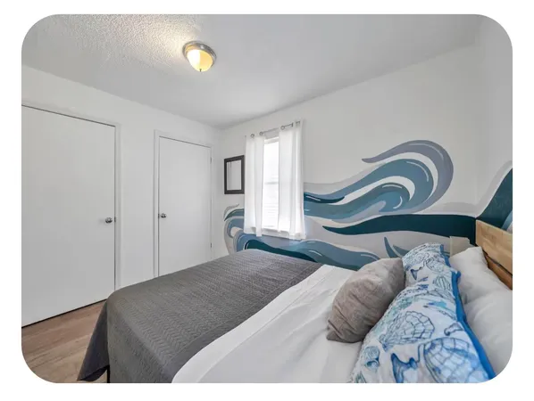 a spacious bedroom with a bed a couch and chandelier