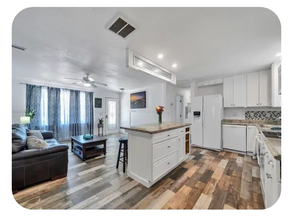 a kitchen with granite countertop a sink cabinets and wooden floor