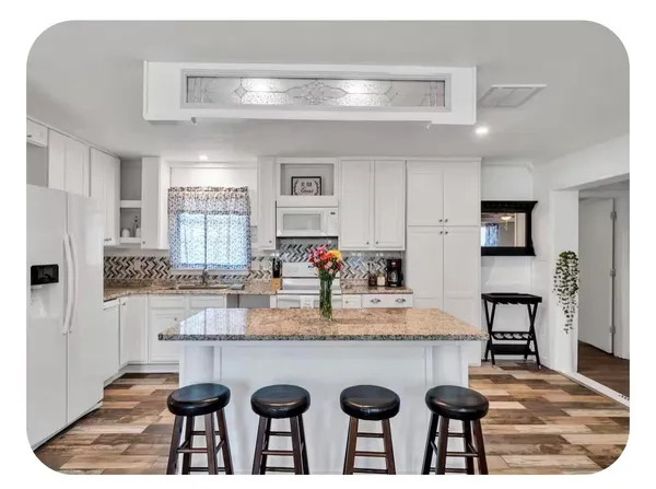 a kitchen with kitchen island granite countertop a table chairs sink and cabinets