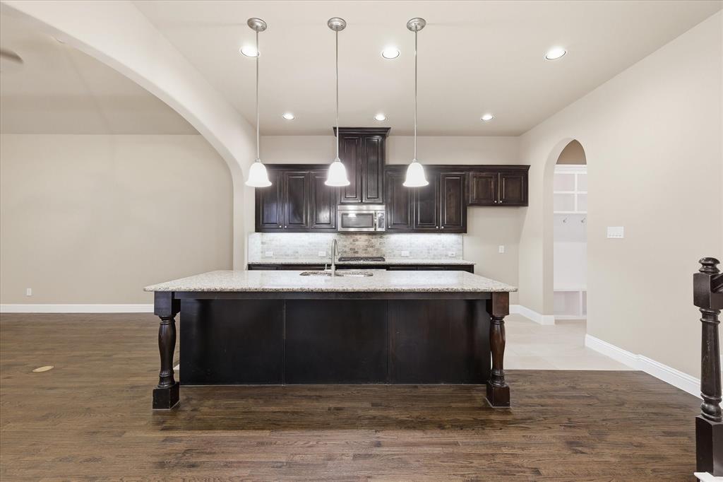 768 Huntingdon Street Coppell, TX 75019 - Photo 15 of 37 Beautiful open kitchen featuring a large granite island, pendant lighting, rich dark cabinetry, and seamless flow into the main living areas.