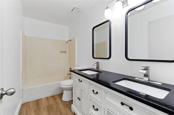 a bathroom with a double vanity sink toilet mirror and bathtub