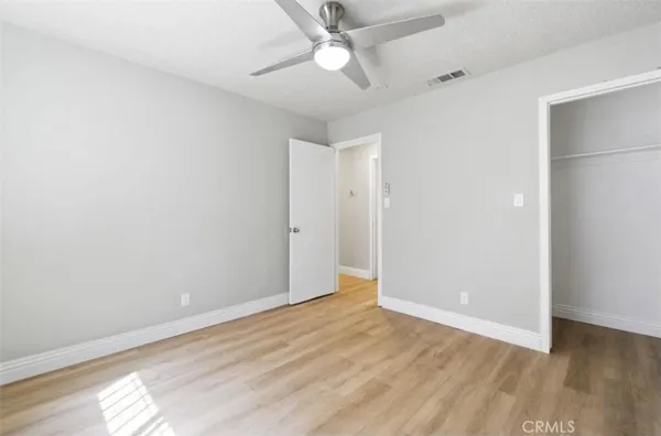an empty room with wooden floor and a ceiling fan