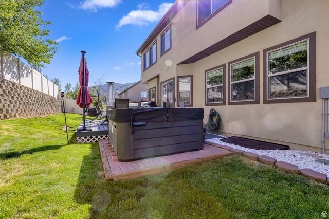 2005 Redtail Way Layton, UT 84040 - Photo 34 of 37 Expansive backyard featuring a built-in hot tub on a brick paver base, a multi-level deck with lattice skirting, and a manicured lawn