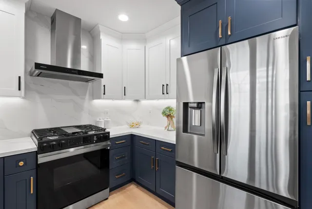a kitchen with stainless steel appliances a refrigerator a stove and white cabinets