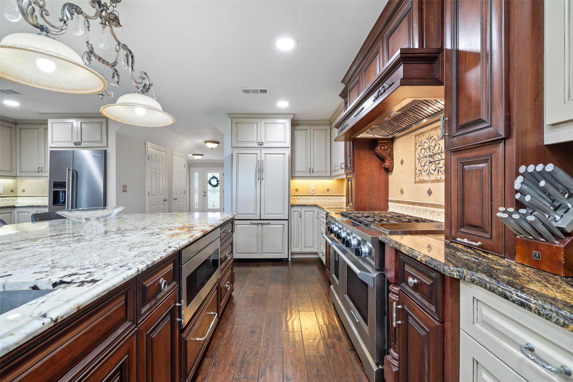 17700 North Rim Drive Leander, TX 78641 - Photo 15 of 38 Kitchen featuring built in appliances, light stone countertops, recessed lighting, dark wood-type flooring, and custom exhaust hood