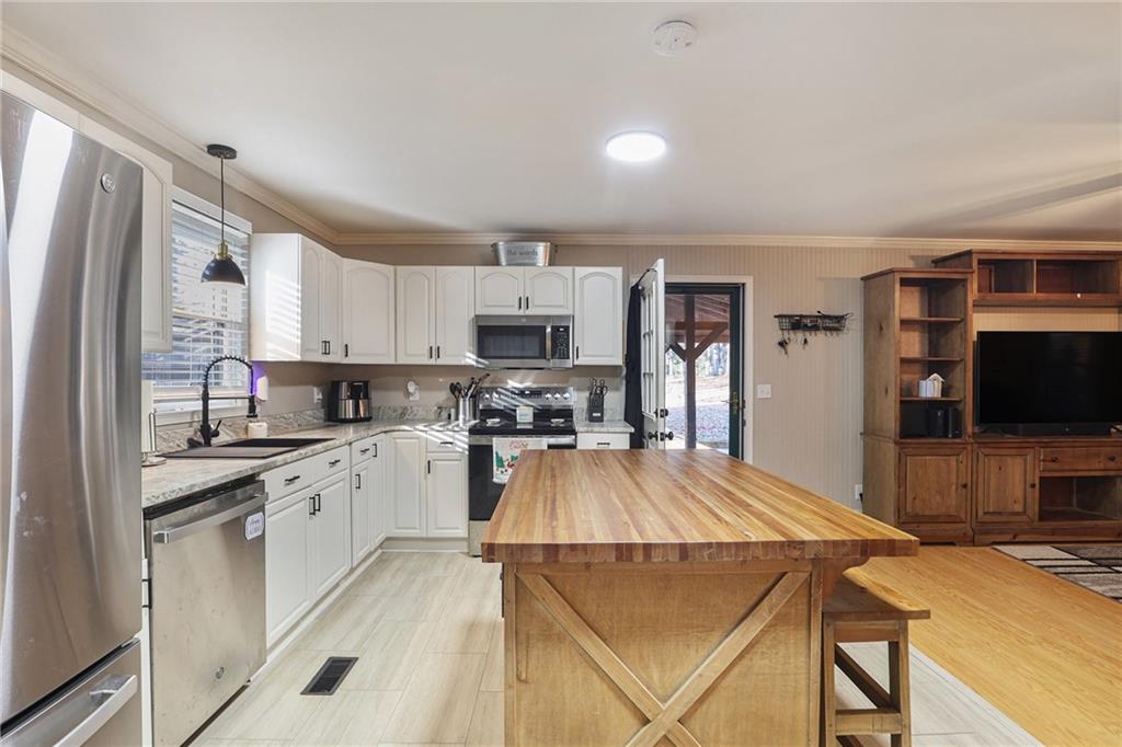 315 Laurel Road Carrollton, GA 30117 - Photo 12 of 30 a kitchen with stainless steel appliances granite countertop a refrigerator a stove top oven a sink dishwasher and white cabinets with wooden floor