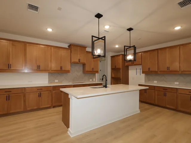 a large kitchen with stainless steel appliances granite countertop a sink a stove and a wooden floors