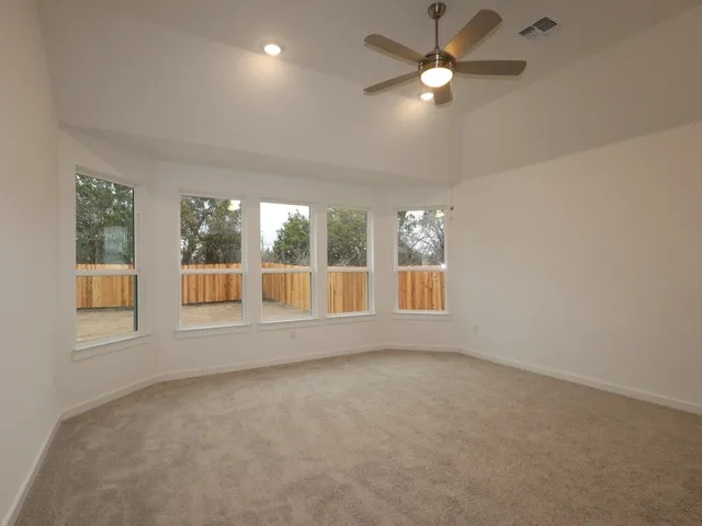 a view of an empty room with a window and kitchen view