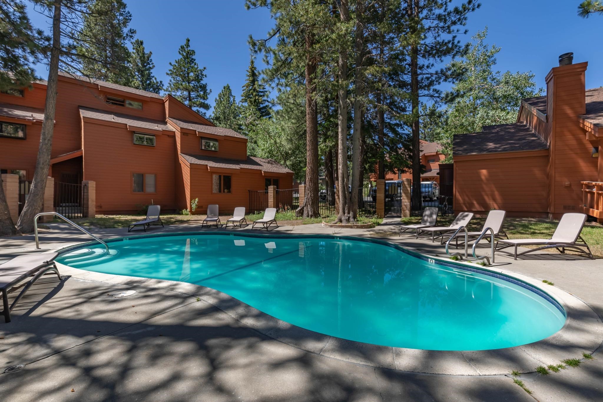 3392 Chateau Road, Unit 29 Mammoth Lakes, CA 93546 - Photo 30 of 30 Freeform swimming pool with concrete decking, surrounded by mature pine trees and building exteriors featuring wood siding