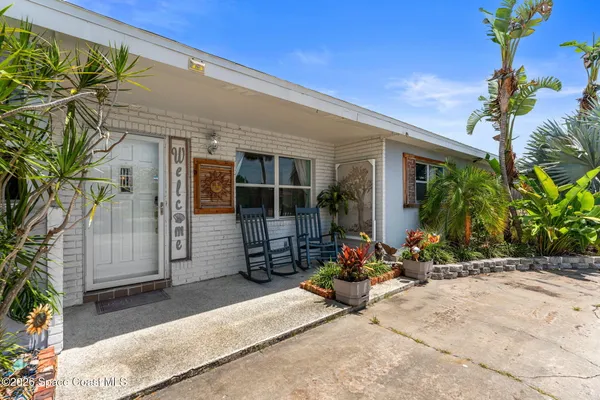 a view of a brick house with potted plants in front of door