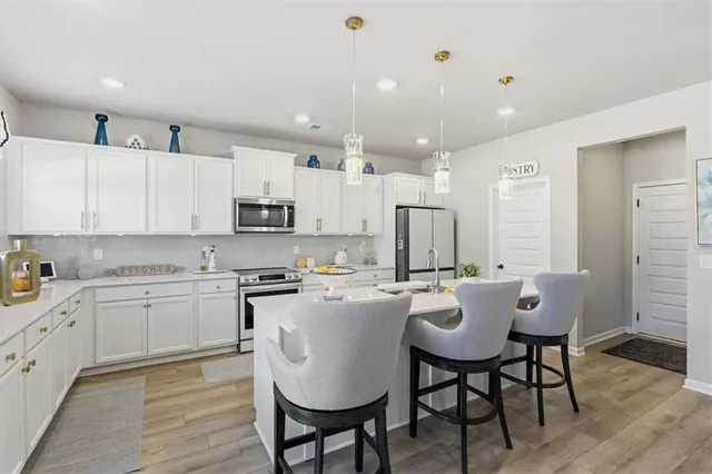 a kitchen with a sink dishwasher a dining table and chairs with wooden floor