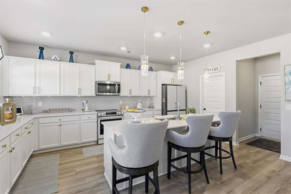 1171 Bodega Loop Locust Grove, GA 30248 - Photo 13 of 57 a large kitchen with kitchen island a dining table and chairs