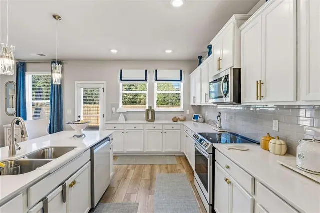 a large kitchen with sink a refrigerator and chairs