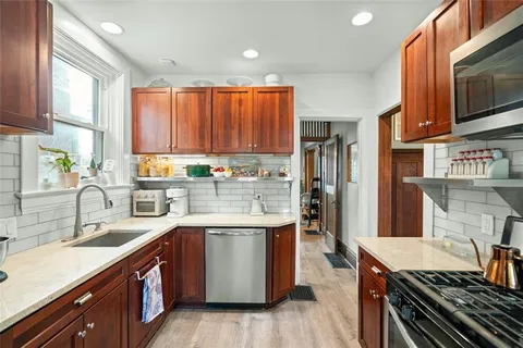 a kitchen with stainless steel appliances granite countertop a stove a sink dishwasher and a microwave oven with wooden cabinets