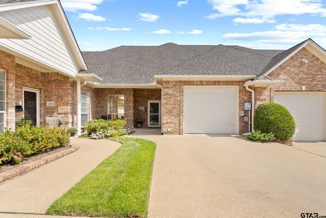 a front view of a house with a yard and potted plants