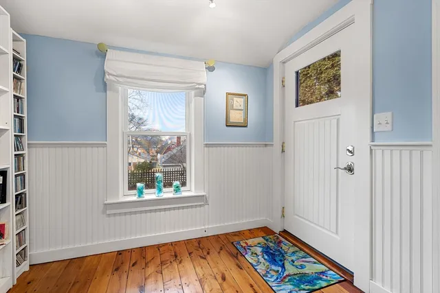 a view of an empty room with window and wooden floor