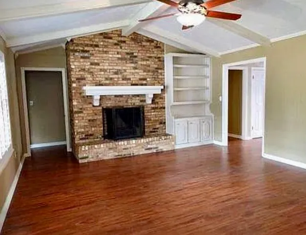 a view of empty room with wooden floor and fireplace