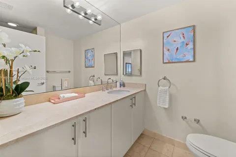 a bathroom with a granite countertop sink a toilet and a mirror