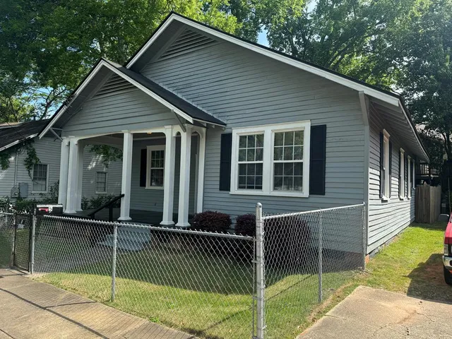 a view of a house with a yard and a large tree front of house