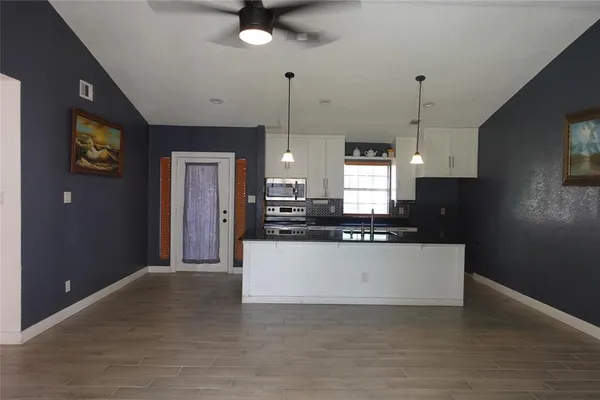 a view of a kitchen with kitchen island a sink wooden floor and a refrigerator