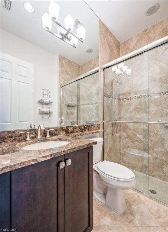Undisclosed Address Naples, FL 34119 - Photo 23 of 32 a bathroom with a granite countertop sink a toilet a mirror and shower