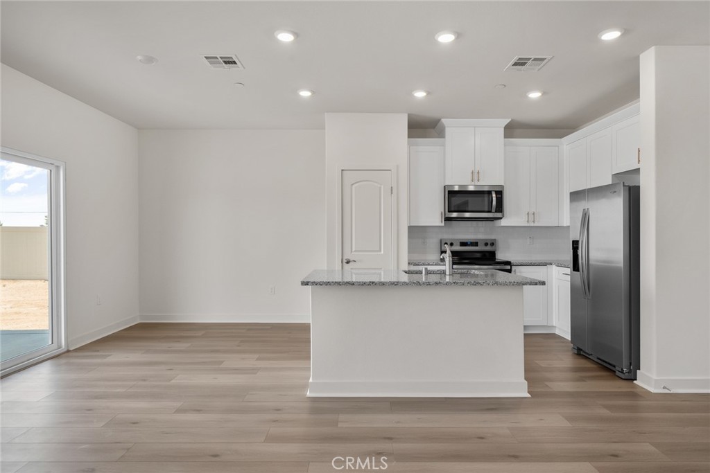 14812 Indigo Street Apple Valley, CA 92307 - Photo 4 of 7 a kitchen with stainless steel appliances granite countertop a refrigerator stove a sink and white cabinets