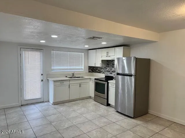 a kitchen with granite countertop a refrigerator and a stove top oven