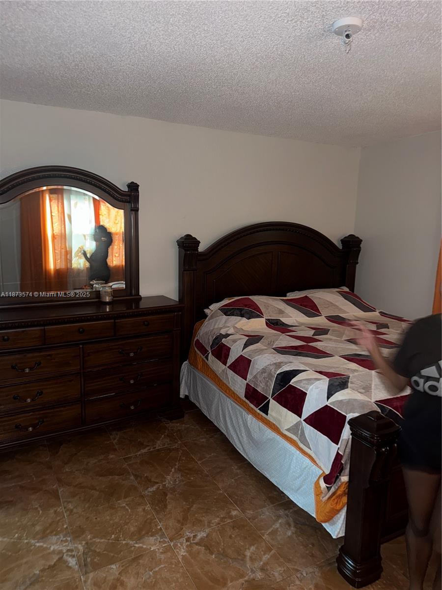 769 Southwest 8th Terrace Florida City, FL 33034 - Photo 11 of 25 a bedroom with a bed and a flat tv screen on dresser