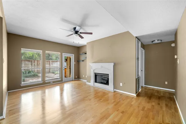 a view of an empty room with a fireplace and wooden floor