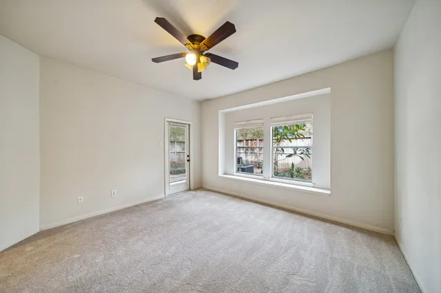 an empty room with windows and a ceiling fan