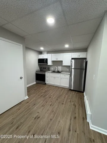 a large kitchen with a wooden floor and stainless steel appliances