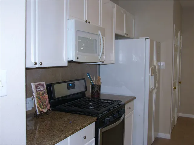 a kitchen with granite countertop white cabinets and stainless steel appliances