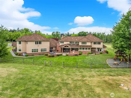 a view of a house with a big yard and large trees