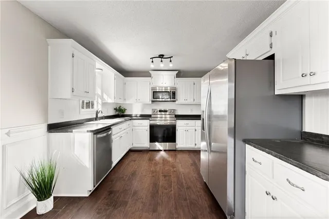 a kitchen with white cabinets stainless steel appliances and a window