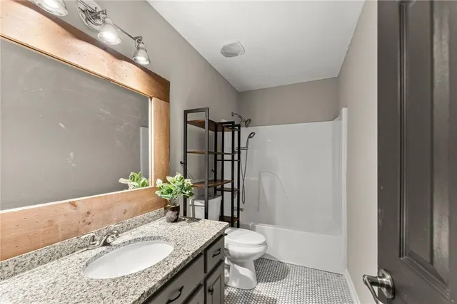 a bathroom with a granite countertop sink a toilet a mirror and shower
