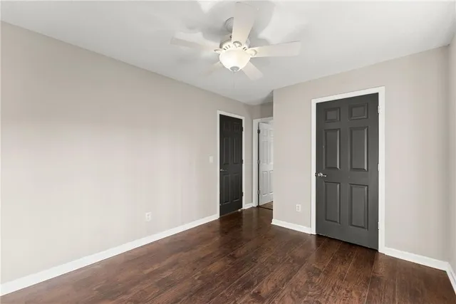 an empty room with wooden floor chandelier fan and windows
