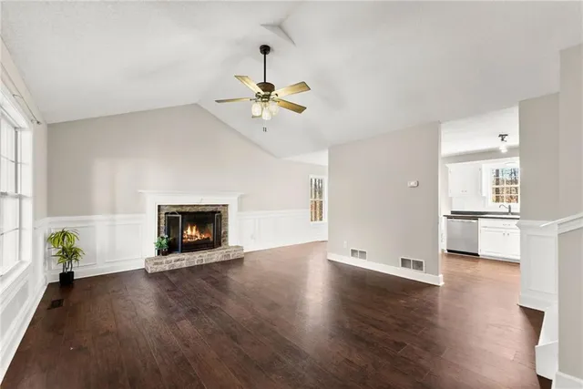 a view of an empty room with a kitchen and wooden floor