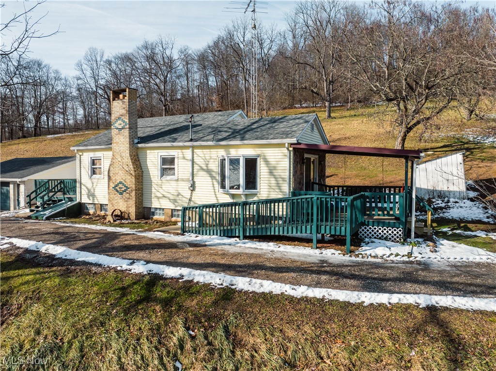 View of front of property featuring a chimney, roof with shingles, and a porch