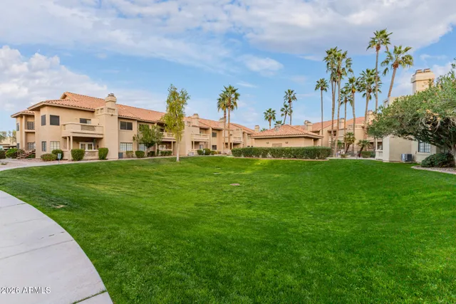 a view of a white house with a big yard and potted plants