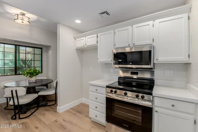 a kitchen with stainless steel appliances a stove a microwave and white cabinets